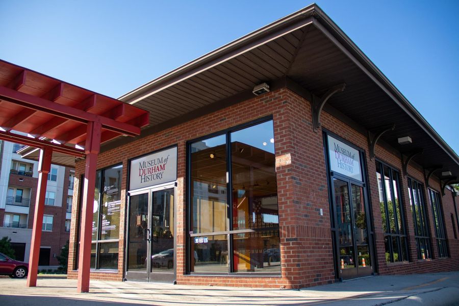 A blue sky hangs over the brick and glass entrance to the Museum of Durham History.