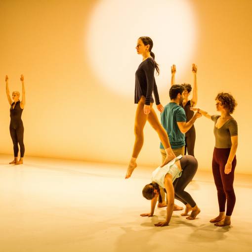Dancers performing against a glowing cream backdrop.