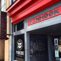 The storefront of The Pinhook displays gray walls and a red overhang along with their logo.