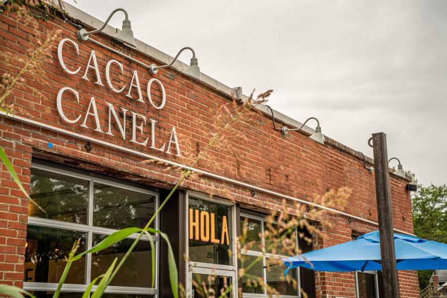 Clouds float in behind the storefront of Cocoa Cinnamon's Lakewood location, giving off a cozy and calm atmosphere.