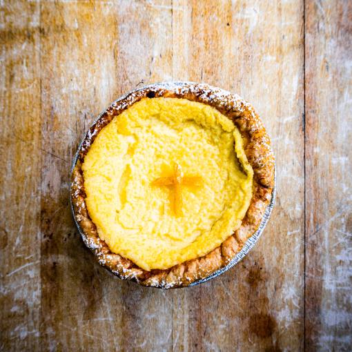 A wood table backgrounds a homemade lemon tart from Rose&#039;s Noodles, Dumplings, &amp; Sweets in Durham, NC.