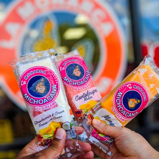 Hands hold up an assortment of frozen treats in front of La Monarca Michoacana in Durham, NC.