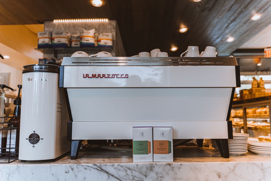 Two bags of Counter Culture Coffee sit in front of an espresso machine at Mad Hatter Cafe + Bakeshop in Durham, NC.
