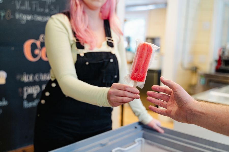 An employee hands a popsicle to a customer at LocoPops in Durham
