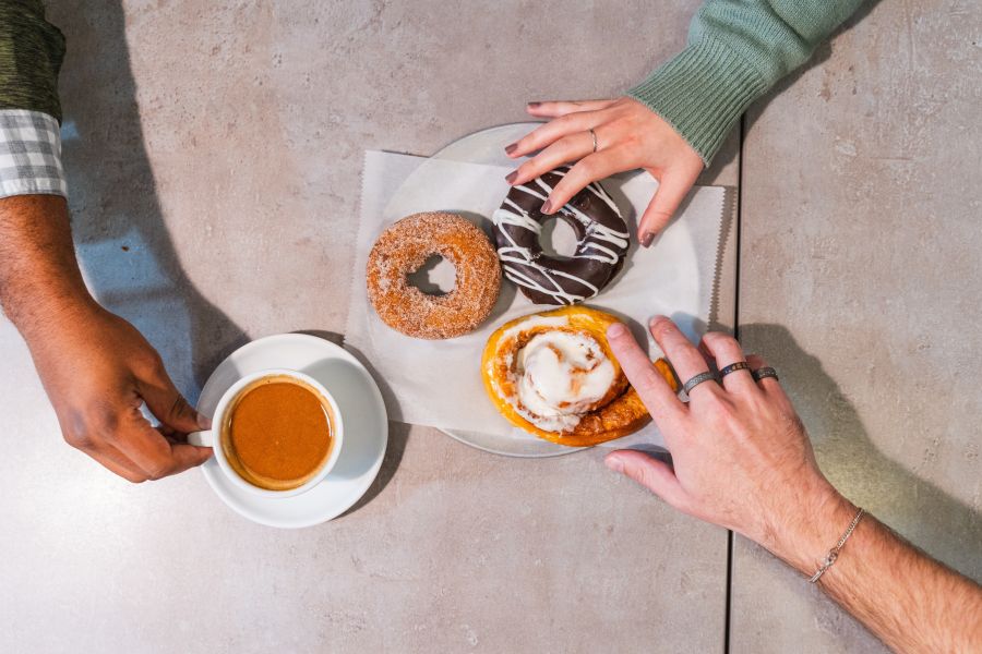Hands reach for colorful, sweet donuts and savory coffee from Monuts in Durham, NC.