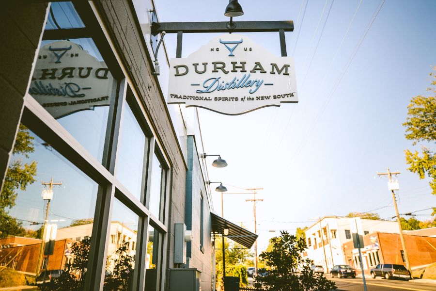 Sun shines on the Durham Distillery sign and the street behind it.