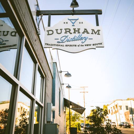 Sun shines on the Durham Distillery sign and the street behind it.