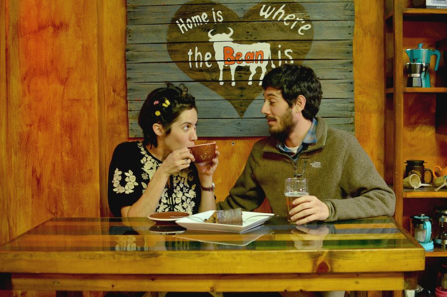 Two customers chat and enjoy drinks under low lighting at a booth at Bean Traders.