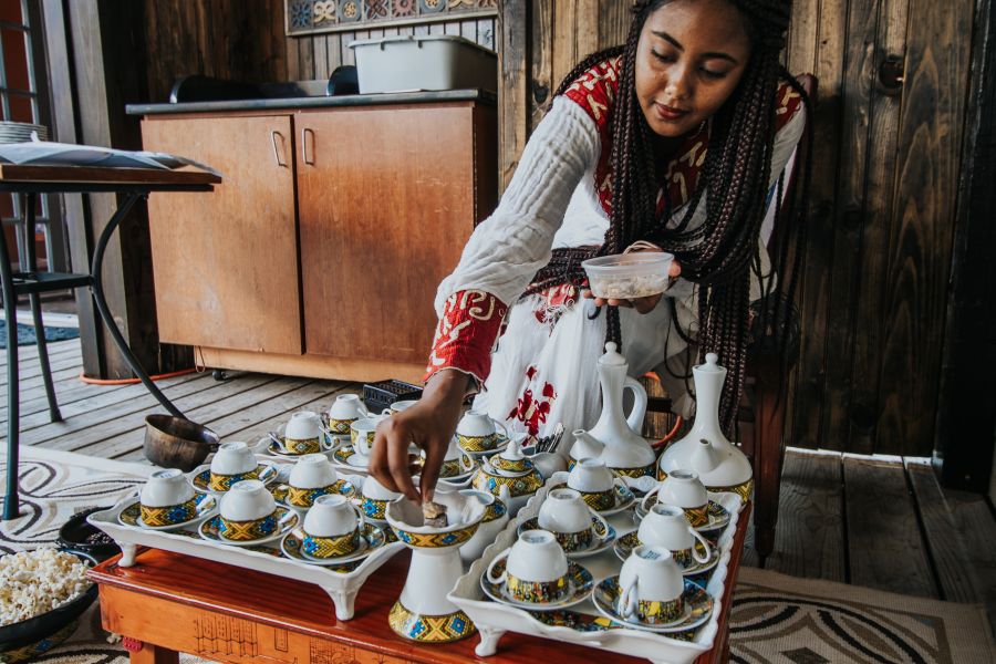 A woman makes coffee, sitting over a tray of many colorful coffee mugs at Gojo in Durham, NC.
