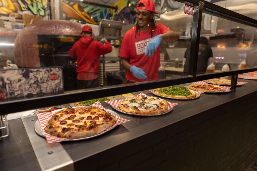 Cooks stand over a line of freshly made pizzas at Boxcar in Durham, NC.