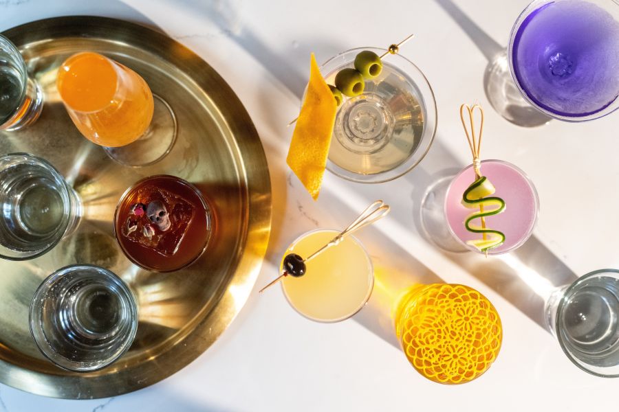 A colorful array of drinks sit on a white table at Corpse Reviver in Durham, NC.