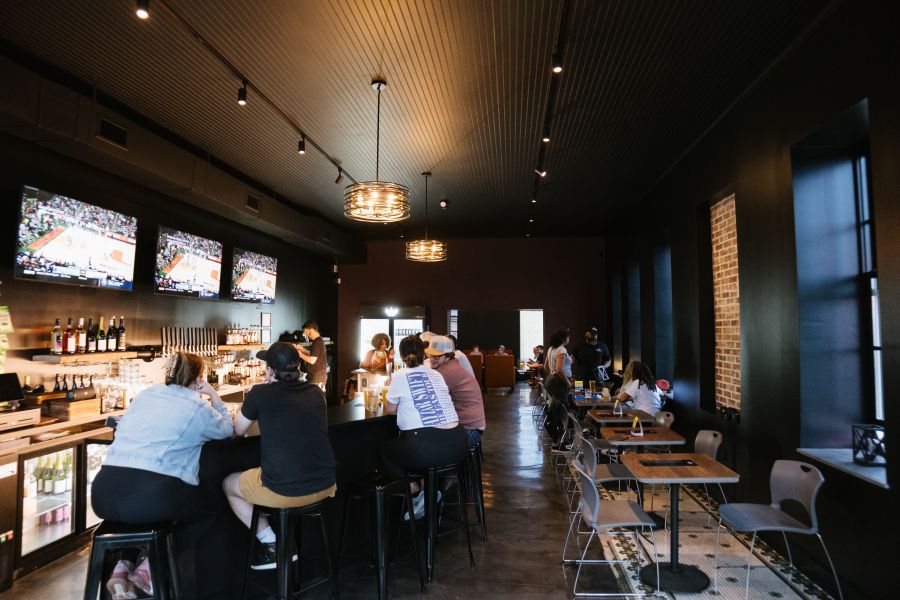 The slick, black interior of Proximity Brewing in East Durham. Customers fill the bar seats.