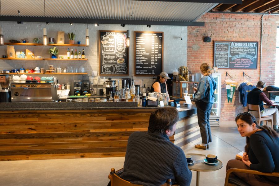 Patrons sit in chairs while a visitor orders a coffee at the counter at Yonderlust in Durham, NC.