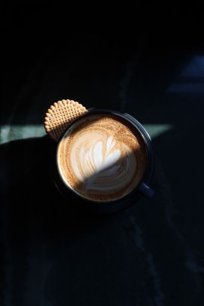 Light filters over a brown and white latte in a black mug on the table at Aaktun.