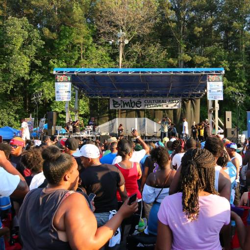 Many Bimbé festival goers gather in front of a stage enjoying live music.