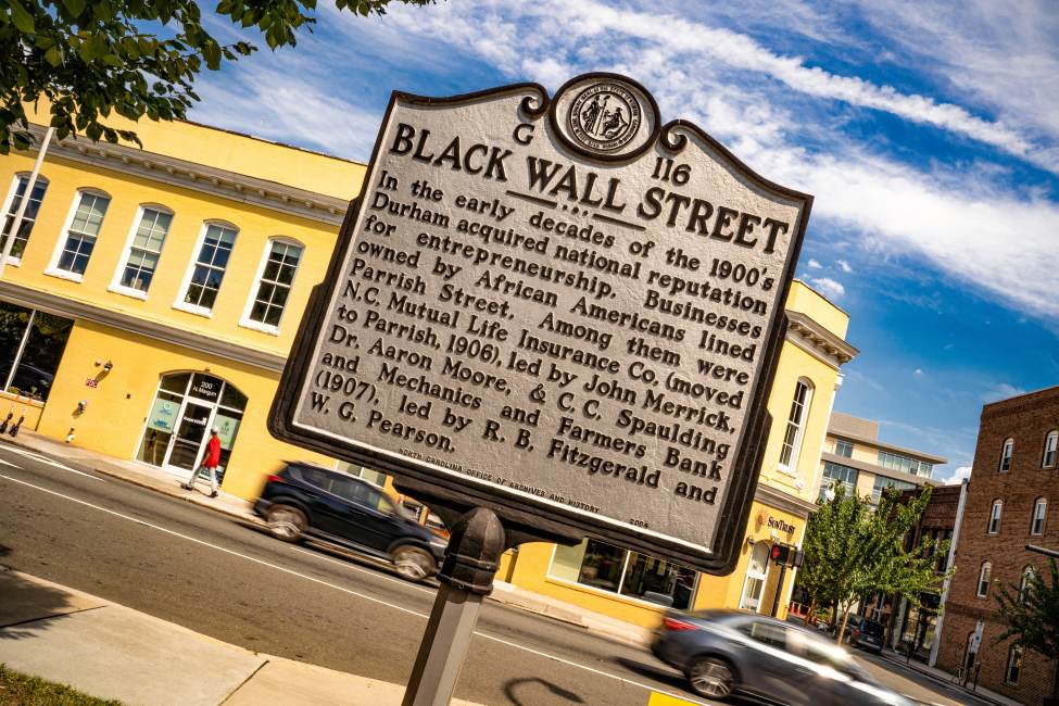 A sign stands on Parrish Street with information about Black Wall Street in Durham.