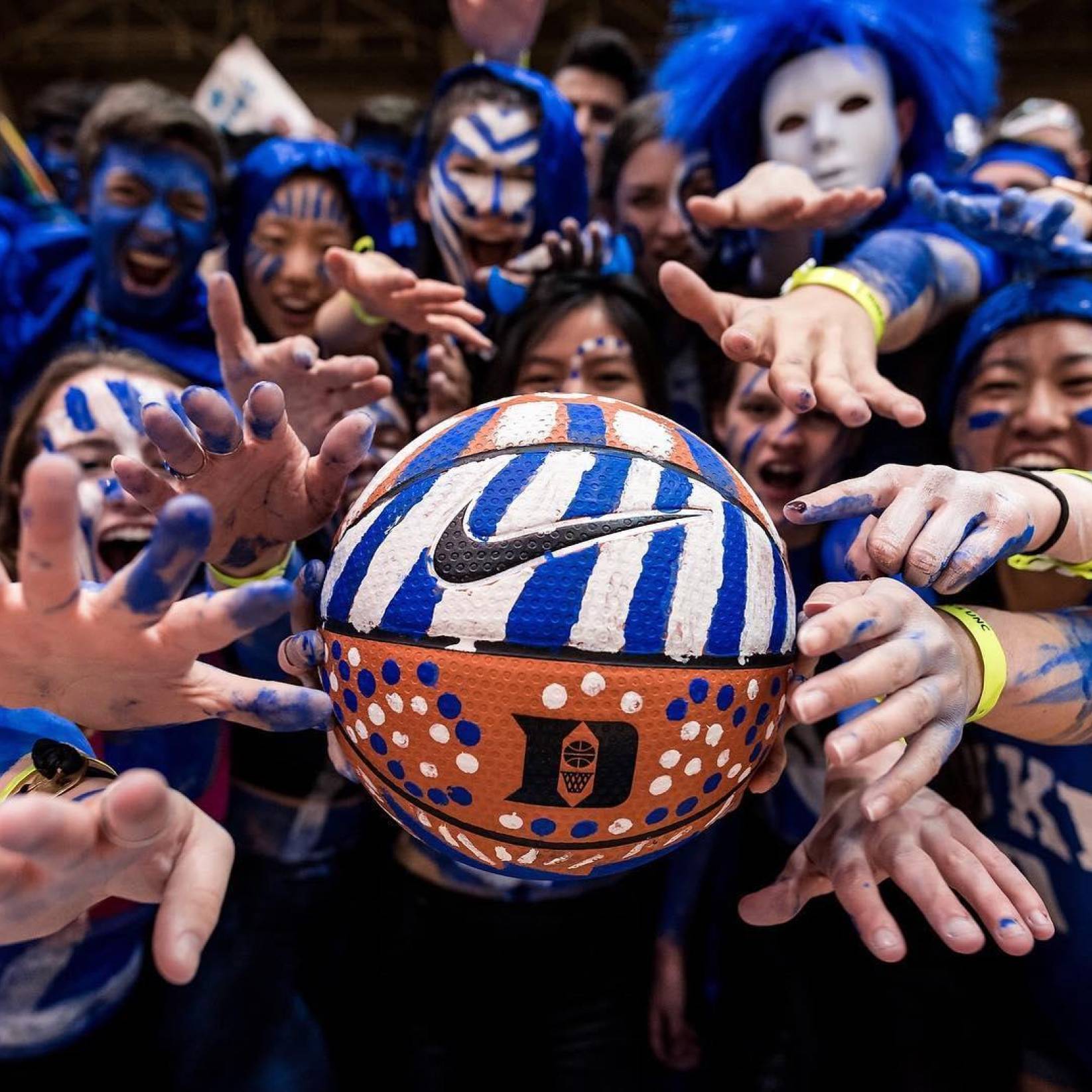 Duke fans hold a basketball that is painted to represent the Duke Blue Devils.