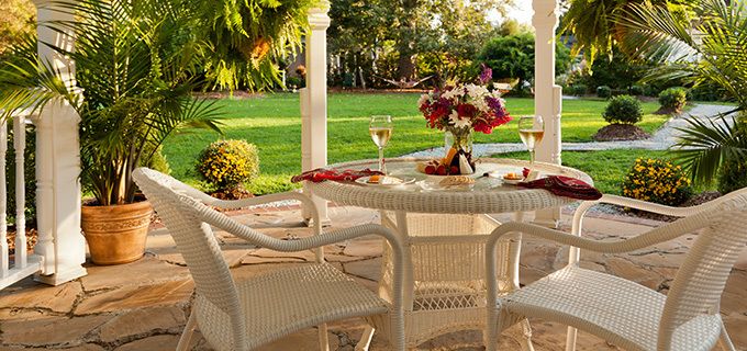An outdoor dining table is set on a deck in front of the lawn at Arrowhead Inn Bed & Breakfast.