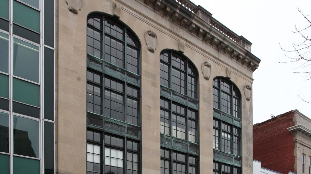 The bricks on the Old Hill Building sandwich the tall, paneled glass windows.