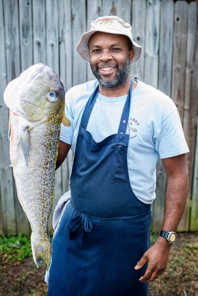 Chef Ricky Moore holds up a fish for the camera.