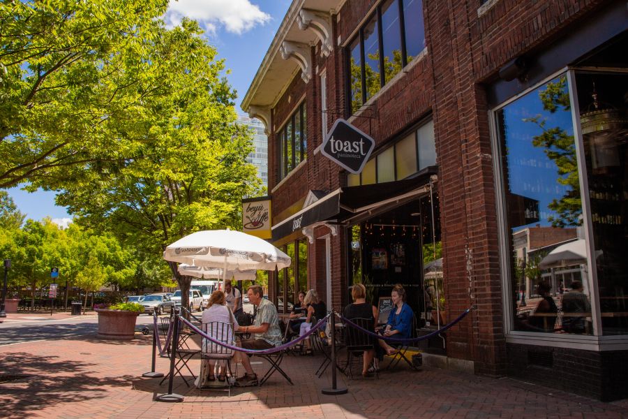 Spring trees hang over the entrance sign to Toast in Durham.