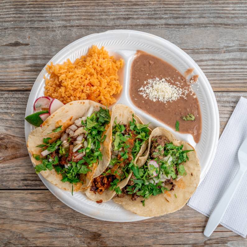 A plate of tacos, rice, and beans sits on the patio at Taqueria La Vaquita in Durham, NC.
