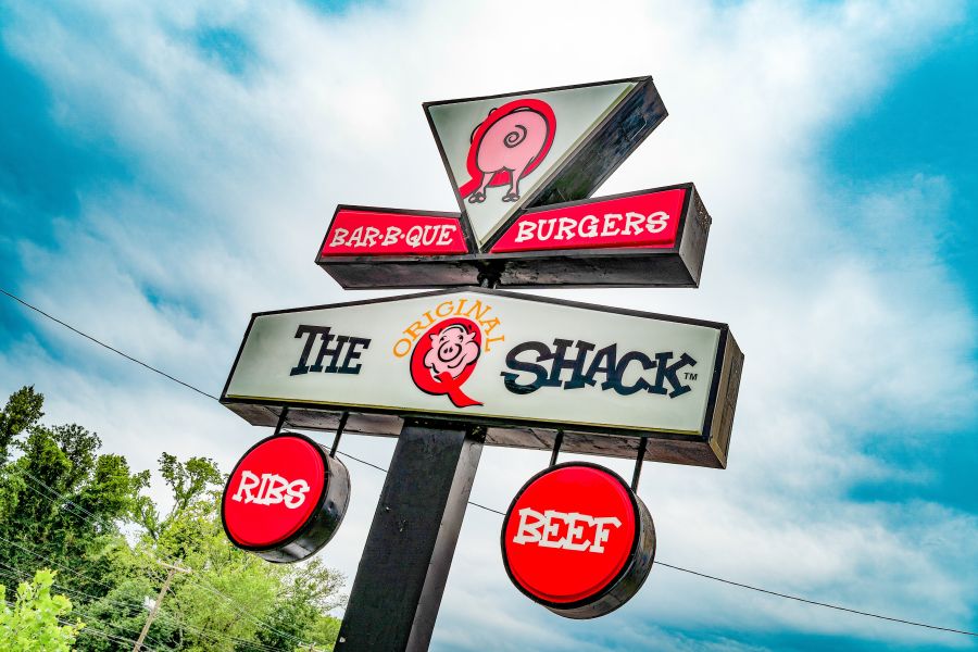 The sign for The Original Q Shack stands tall on a sunny day, beckoning customers in for some tasty Durham barbecue.
