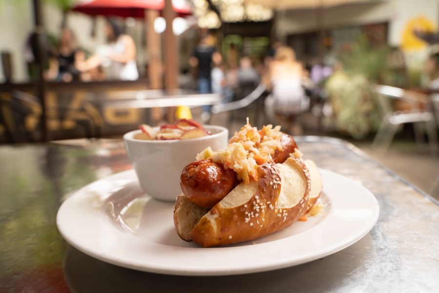 A bratwurst sits steaming in a bun on the table at Guglhupf