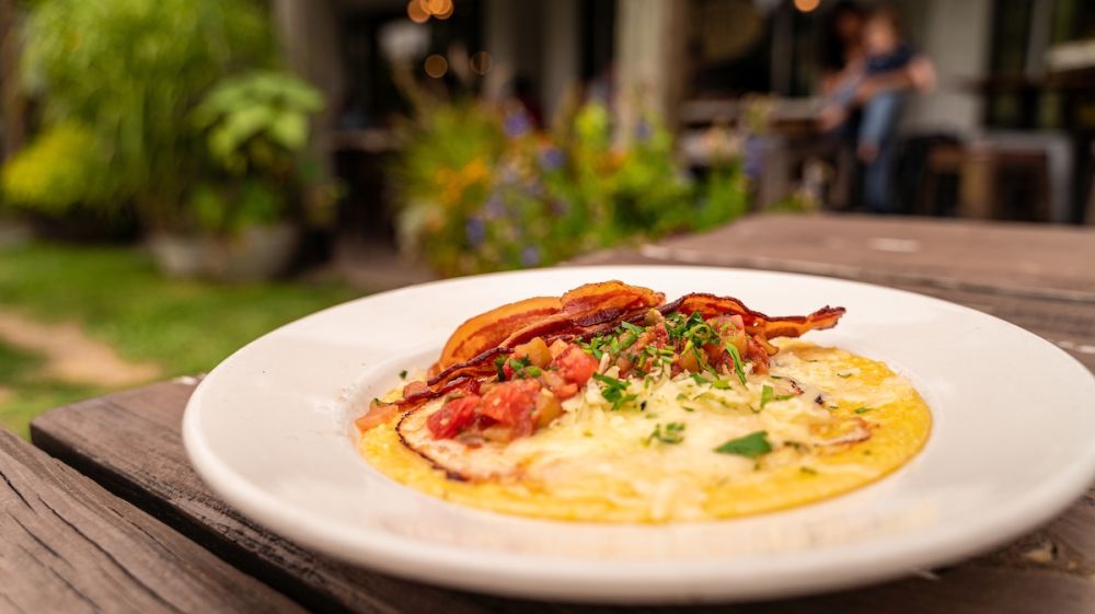 A bacon and grits bowl from Foster's Market in Durham foregrounds the storefront.
