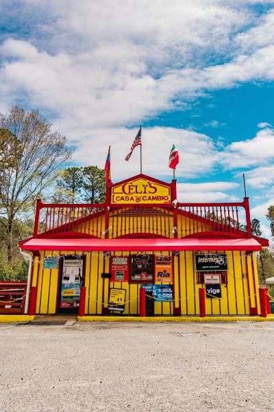 The yellow and red Cely's Casa De Cambio sits as the front of Tacos Nacos.