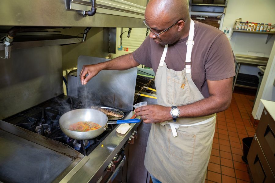 Chef Ricky Moore sprinkles seasoning into a pan at Saltbox Seafood Joint.