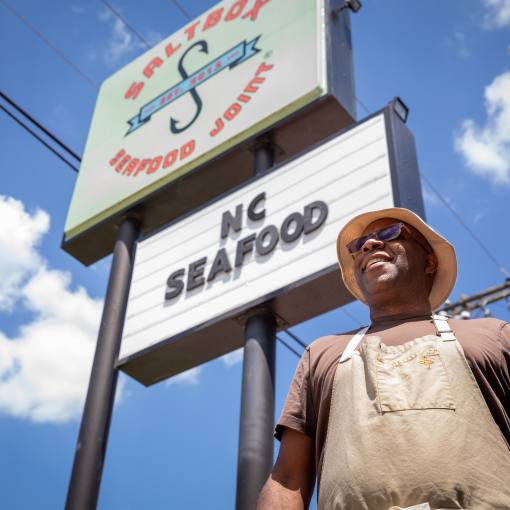 Chef Ricky Moore stands outside Saltbox Seafood Joint on a sunny day.