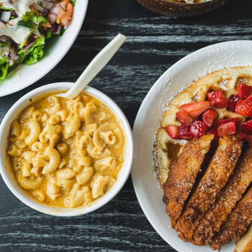 A spread of tasty vegan dishes like mac n' cheese and chicken and waffles lay on a table at Pure Vegan Cafe.