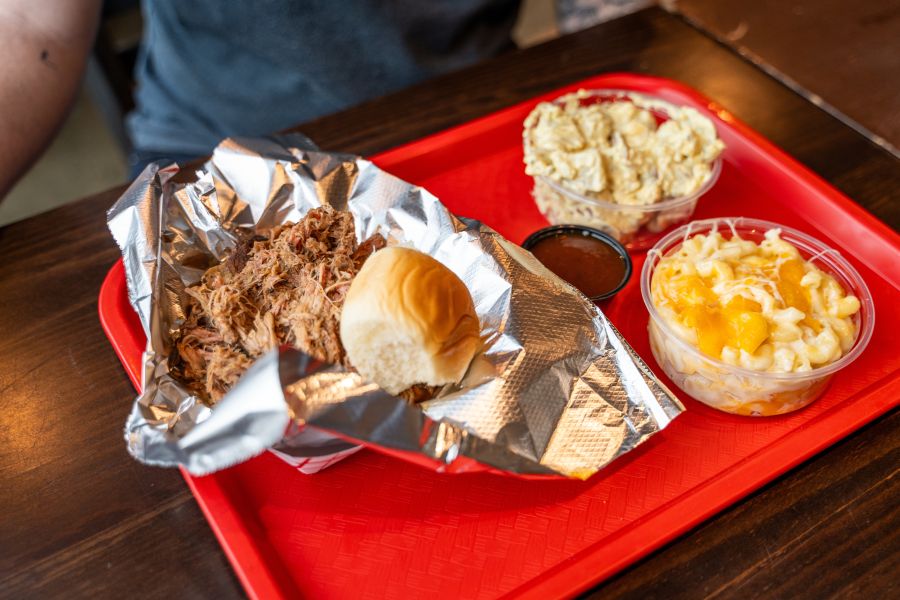 A customer waits to dig into a plate of pulled pork, mac n' cheese and potato salad from Mike D's.