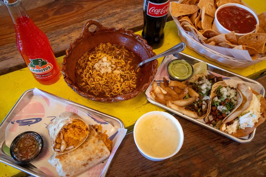 A generous spread of tacos, a burito, and guiso sit on a table at Fonda Lupita.