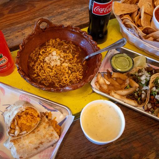 A generous spread of tacos, a burito, and guiso sit on a table at Fonda Lupita.