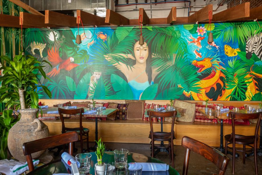 A mural depicting a woman in a jungle surrounded by animals adorns the wall at Krill in Durham, NC.