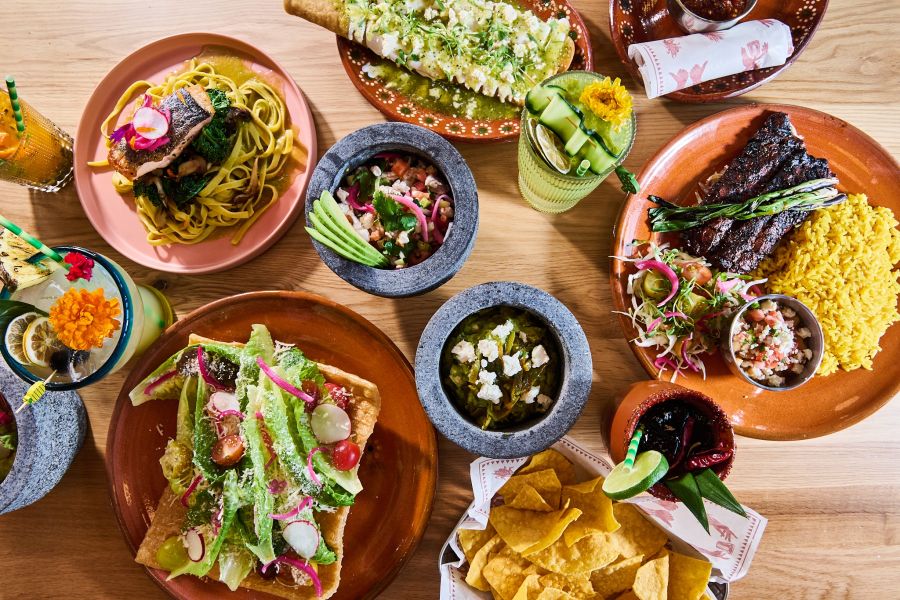 Plates full of tacos and other colorful foods sit next to each other surrounding bowls of salsa at TaTaco in Durham.