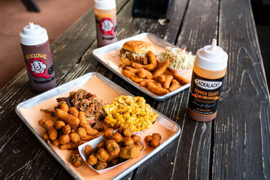 Two trays of delicious barbecue and tantalizing sides sit waiting to be enjoyed at The Q Shack.