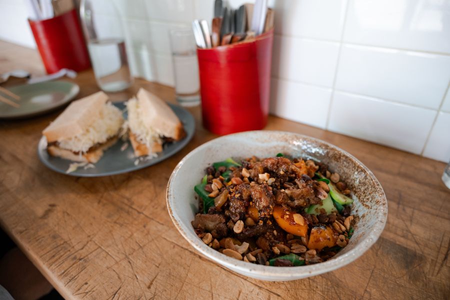 A bowl of noodles sits in front of a plated sandwich on the counter at Rose's in Durham, NC.