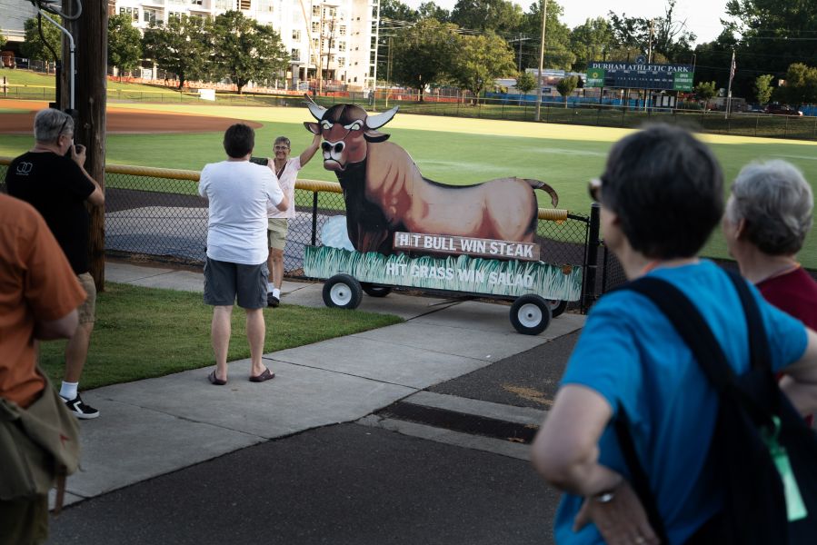 A tourist poses with the bull sign from the original Historic Durham Athletic Park.