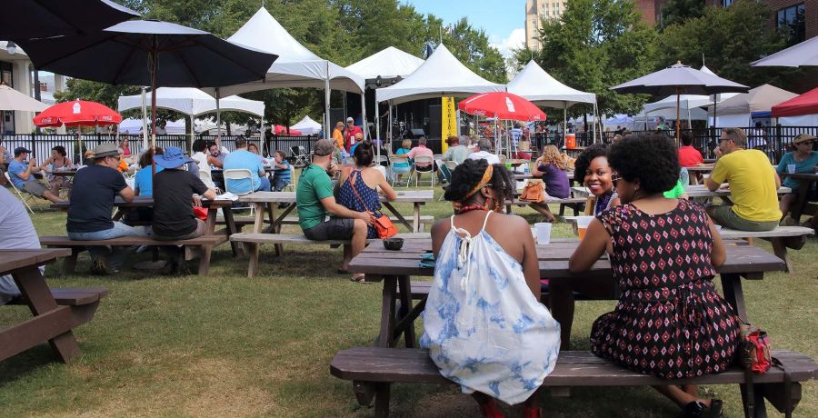 Festival goers sit on picnic tables outside at CenterFest in Durham, NC