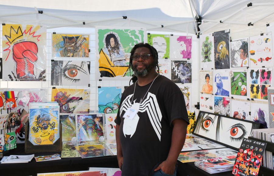 An artist stands in front of paintings for sale at Centerfest in Durham, NC.