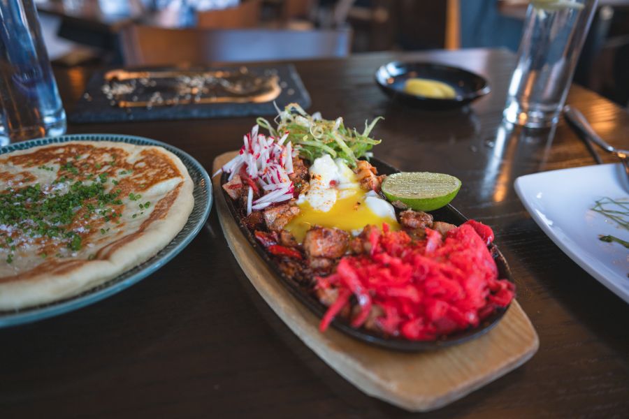 Two plates of colorful food sit on a table at Juju in Durham.