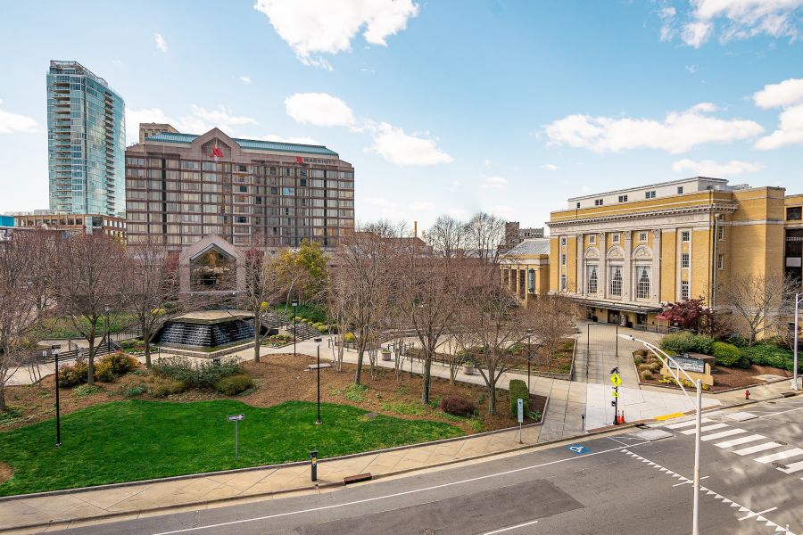 Clouds roll through a blue sky over the yellow facade of the Carolina Theatre.