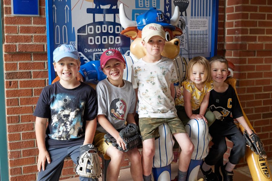 A group of children sit together at the Durham Bulls Athletic Park.