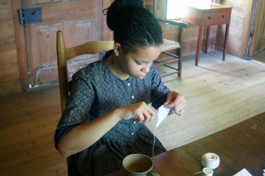 A reenactor shows the work people would have done inside the home at Duke Homestead.