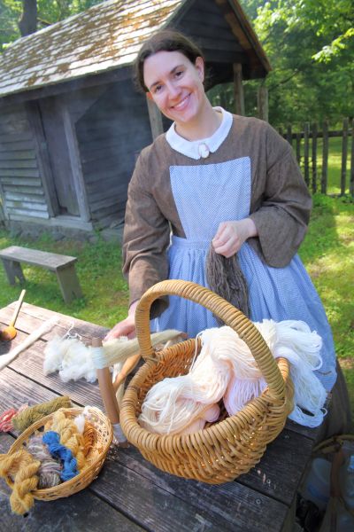 A reenactor stands outside by a table at Duke Homestead in Durham