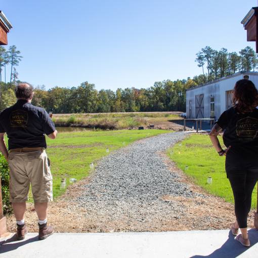 Two employees of Mystic Farm & Distillery stand with their backs to the door, looking out onto the farm.