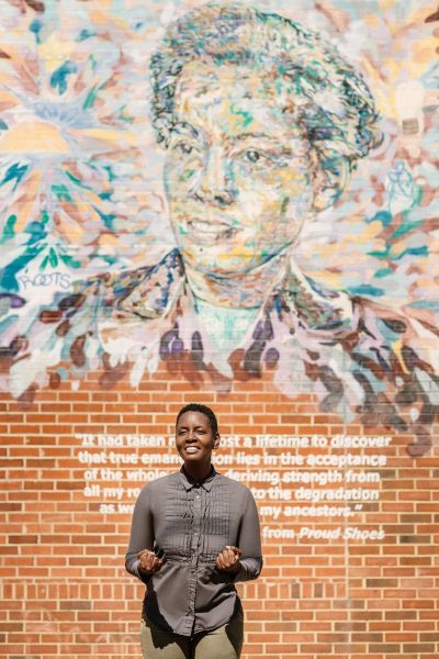 Whistlestop Tours's Aya Shabu poses in front of one of Durham's Civil Rights Murals.